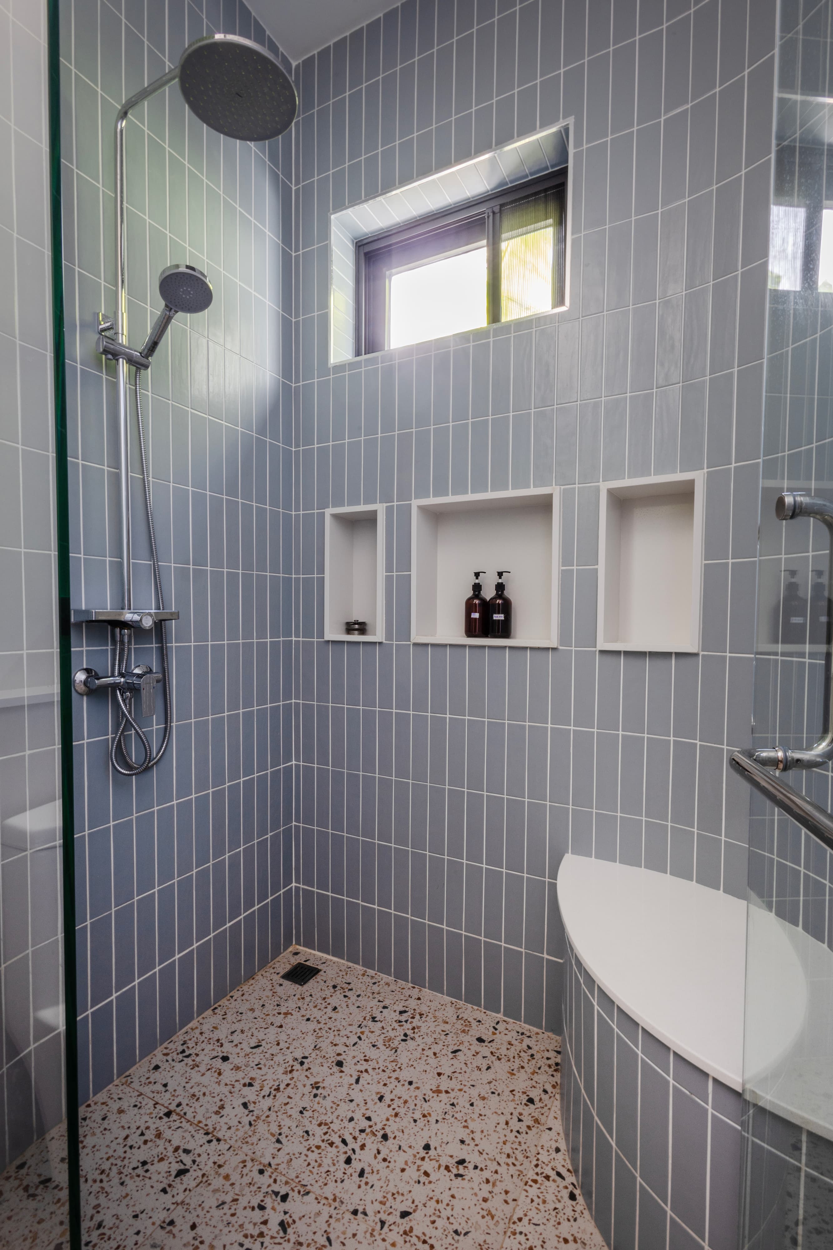 Walk-in shower with grey tile and terrazzo floor — Barefoot Villas